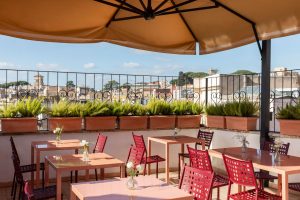Terrazza panoramica per gli ospiti in un boutique hotel nel centro di Roma, con tavoli all'aperto dove gli ospiti possono gustare la colazione ammirando la vista sulla città in un'atmosfera luminosa ed elegante – Barberini Retreat Boutique Hotel, BZAR hotels a Roma