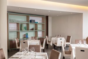Elegant restaurant dining room with upholstered seating, tables and artistic wall, taste experience in Sarzana, Liguria - Hotel Al Sant'Andrea, BZAR hotels in Liguria